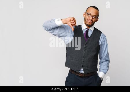 un jeune homme d'affaires noir avec une expression dissidente sérieuse et déplaît avec le pouce en désapprobation Banque D'Images