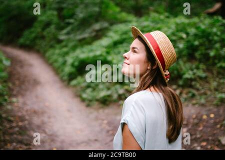 Photo en plein air d'une jeune fille qui se rafraîchise dans une belle forêt. Joyeuse jeune jolie femme en chapeau de paille vintage posant dans le parc. Jolie jeune femme Banque D'Images