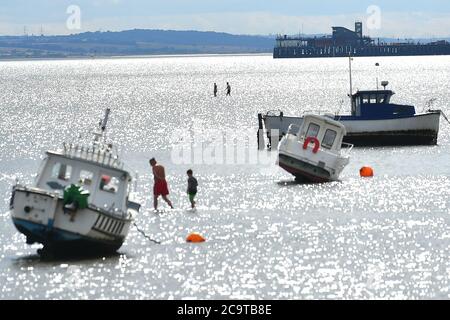 Les gens pataugent sur la plage à marée basse à Southend alors que le temps chaud continue. Banque D'Images