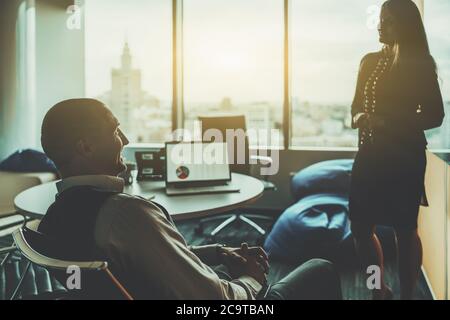 Silhouettes de deux hommes d'affaires ayant une réunion dans une salle de réunion typique au dernier étage d'un gratte-ciel de bureau contemporain Banque D'Images
