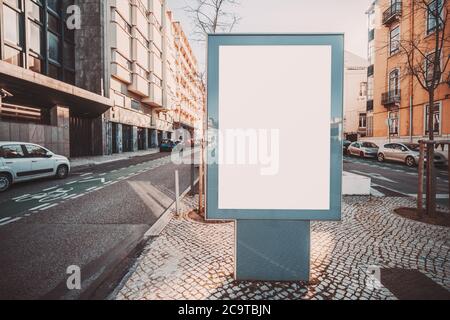 Une maquette de bannière blanche verticale extérieure dans un environnement urbain près de la route ; un espace réservé de modèle d'affiche publicitaire vide sur une pierre de pavage dans un Banque D'Images