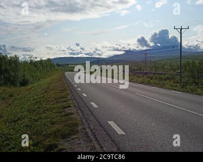 Chemin de fer et chemin de fer sinueux dans le village d'Abisko et parc national avec forêt de bouleau et montagnes, ciel bleu d'été nuages Banque D'Images