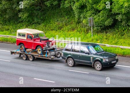 1996 90s rouge SWB Canvas Land Rover série IIa pick-up sur une remorque tractée par Land Rover Range Rover HSE TD6 Auto ; véhicules mobiles pour la circulation routière, voitures conduisant un véhicule sur les routes britanniques, 90s moteurs classiques, conduite sur le réseau autoroutier M6. Banque D'Images