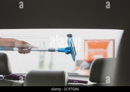 Employé utilisant une éponge pour nettoyer un pare-brise de voiture à la station-service. Banque D'Images