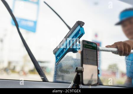 Employé utilisant une éponge pour nettoyer un pare-brise de voiture à la station-service. Banque D'Images