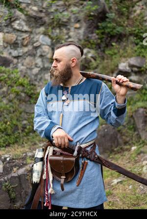 Un homme en vêtements médiévaux est entouré d'une hache dans les ruines d'un ancien château, une reconstitution historique viking Banque D'Images