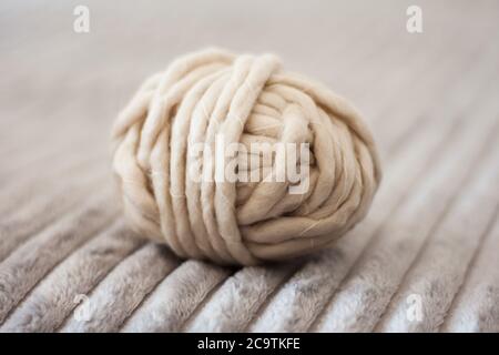 une boule de fil blanc acrylique pour tricoter sur un couvre-lit gris, intérieur confortable Banque D'Images