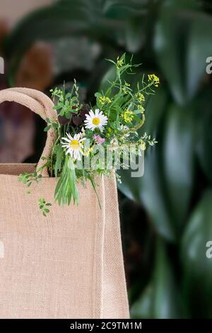 Bouquet de fleurs sauvages dans un sac en toile, fond naturel d'été. Carte de vœux, saisons, concept de vacances Banque D'Images