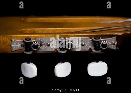 Têtes de machine de guitare acoustique isolées sur fond sombre Banque D'Images