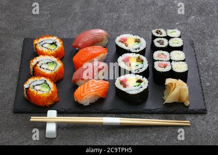 assortiment de sushis japonais : rouleaux californiens, maguro (thon), saumon, futomaki (burrito sushi), negitoro (rouleau de thon haché), takuan (radis daikon marinés), Banque D'Images