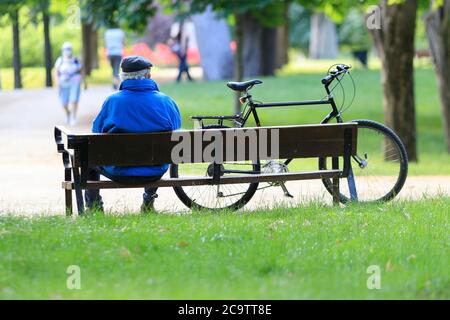 Madrid, Espagne - 31 mai 2020 : homme âgé assis sur un banc à côté de son vélo dans le parc du Retiro à Madrid, Espagne. Banque D'Images