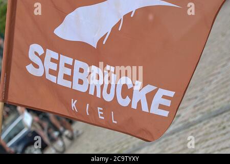01.08.2020, Kiel, impression de la démo: 'Seebrucke au lieu de Seehofer - même combat, année différente!', à laquelle l'organisateur, Seebrucke Kiel, a appelé. Le but du rallye était la place de l'hôtel de ville. Le Seebrucke appelle à un programme d'admission de l'Etat SH pour les réfugiés des camps grecs, à la dépénalisation du sauvetage en mer et du vol! La fin de la répression contre le sauvetage en mer des civils, la libération des navires, la fin de la politique raciste de forclusion. Sur l'image le drapeau avec le logo de la Seebrucke Kiel. | utilisation dans le monde entier Banque D'Images