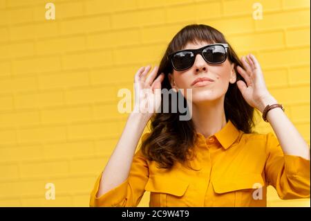 portrait d'une fille en lunettes de soleil contre le mur jaune. Emplacement vide pour écrire du texte. Pleine longueur photo de taille de corps belle étonnante elle sa peau sombre l Banque D'Images