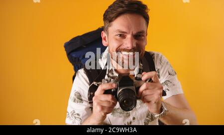 Photo portrait d'un jeune voyageur caucasien barbu souriant avec sac à dos et appareil photo. Photo de haute qualité Banque D'Images