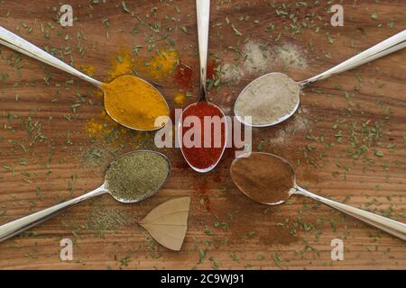 Différentes épices colorées disposées sur des cuillères avec fond en bois Banque D'Images
