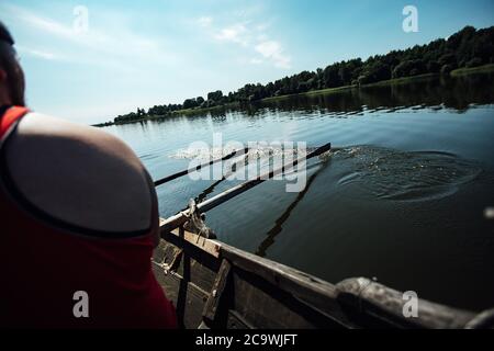 les athlètes en vacances sont engagés dans l'aviron, les nageurs sur des oars en bois frappent l'eau, éclaboussant beaucoup de gouttes autour Banque D'Images