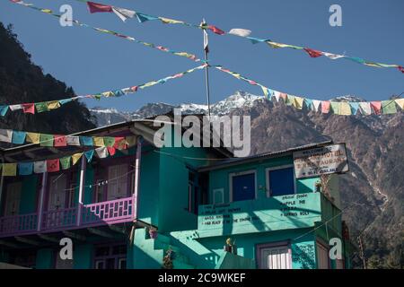 Salon de thé turquoise avec drapeaux de prière bouddhistes sous le pic couvert de neige le long du circuit Annapurna, Himalaya, Népal, Asie Banque D'Images