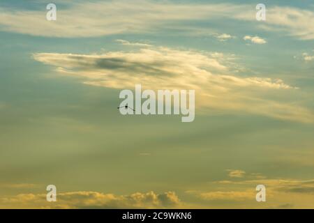 Ambiance nuageux sur le lac de Garde en Italie. Nuages sombres contre le ciel lumineux. Un oiseau vole seul à travers le ciel. Des morceaux de nuage se sont répandus. Banque D'Images