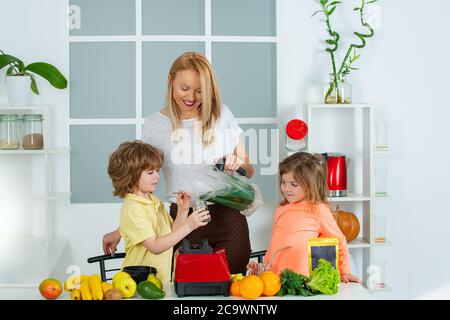 Maman fille et fils préparent un smoothie dans la cuisine. Amusez-vous et jouez avec les légumes. Une alimentation saine et un mode de vie sain pour les enfants. Nutrition végétalienne et a Banque D'Images