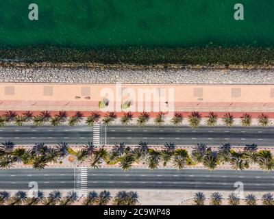 Route côtière avec palmiers et piste de course à pied sur l'île de Marjan à Ras al Khaimah émirat des Émirats arabes Unis vue aérienne Banque D'Images