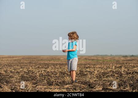 Mignon petit fermier travaillant sur le terrain. Plantation écologique sur terre. Sol noir sur la main de l'enfant. Concept du jour de la Terre. L'été à la campagne. Nature et Banque D'Images