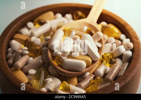 Pilules de médicaments, comprimés et différents médicaments dans un bol en bois avec une cuillère. Banque D'Images