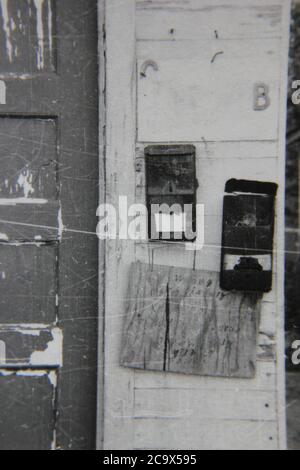 Belle photographie en noir et blanc vintage des années 1970 de boîtes aux lettres accrochées sur le mur d'un immeuble urbain d'appartements. Banque D'Images