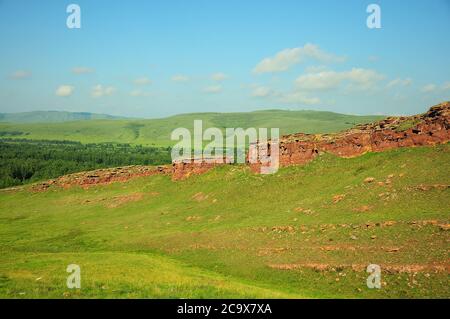 La crête d'une haute colline surcultivée avec de l'herbe et des murs de pierre s'étendant le long du sommet. Coffres de montagne, Khakassia, Sibérie du Sud, Russie. Banque D'Images