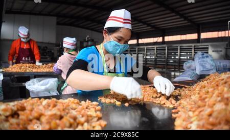 (200803) -- NANNING, 3 août 2020 (Xinhua) -- les travailleurs traitent le kumquat lors d'un atelier de lutte contre la pauvreté dans le comté de Rongan, dans la région autonome de Guangxi Zhuang, dans le sud de la Chine, le 17 avril 2020. Guangxi, une région clé de la mission de lutte contre la pauvreté en Chine, a déployé des efforts constants pour gagner la dure bataille contre la pauvreté en assurant l'emploi de la population pauvre. Tenter de faire travailler les gens a joué un rôle essentiel dans la campagne à grande échelle de Guangxi pour lutter contre la pauvreté, car elle peut sortir toute la famille de la pauvreté. Elle a prouvé le moyen le plus efficace et le plus direct pour aider à combattre la pauvreté. Additio Banque D'Images