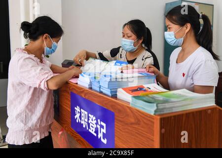 (200803) -- NANNING, le 3 août 2020 (Xinhua) -- des membres du personnel d'une agence de services de l'emploi ont donné des politiques d'aide à l'emploi à un résident relocalisé (L) dans le comté de Xingye, dans la région autonome de Guangxi Zhuang, dans le sud de la Chine, le 2 mai 2020. Guangxi, une région clé de la mission de lutte contre la pauvreté en Chine, a déployé des efforts constants pour gagner la dure bataille contre la pauvreté en assurant l'emploi de la population pauvre. Tenter de faire travailler les gens a joué un rôle essentiel dans la campagne à grande échelle de Guangxi pour lutter contre la pauvreté, car elle peut sortir toute la famille de la pauvreté. Il a prouvé le plus Banque D'Images