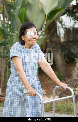 Les personnes âgées utilisent un écran de protection oculaire après une chirurgie de la cataracte dans la cour. Banque D'Images