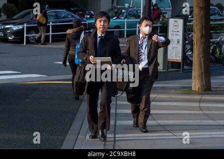 Deux salarymen japonais ou employés de bureau de sexe masculin marchant dans la rue à Shinjuku, Tokyo, Japon Banque D'Images
