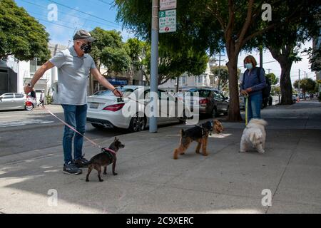 Une paire de randonneurs s'arrête pour une discussion sur le trottoir dans le quartier de Noe Valley à San Francisco, CA, USA. Banque D'Images