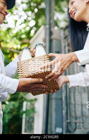 Jeune femme vietnamienne heureuse de recevoir un panier de lait frais en bouteilles de verre Banque D'Images
