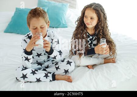 Les enfants boivent du lait. Garçon et fille à la maison. Banque D'Images