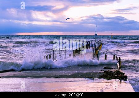 Tempête au bord de l'océan - vagues au-dessus de la jetée du bateau au coucher du soleil Banque D'Images