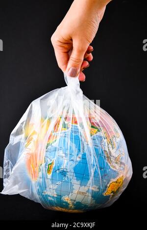 boule sous forme de globe est dans un sac plastique. concept de pollution plastique de la terre. Concept de la Journée mondiale de l'environnement. Globe du monde du jouet en blanc Banque D'Images