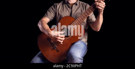 Le guitariste classique joue un morceau de musique. Hommes musicien joue de la guitare classique. Guitariste isolé sur noir. Magnifique instrument acoustique woodem clos Banque D'Images