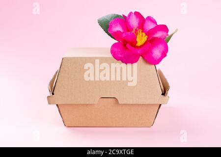 Boîte de hamburger avec fleur rose comme un concept de restauration écologique vaisselle. Banque D'Images