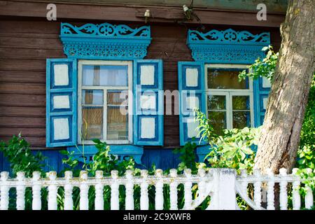 Fenêtres à cadre en bois bleu figuré. Cadre de fenêtre de différentes formes sous forme de bandes verticales et de pastilles. Village en Biélorussie Banque D'Images