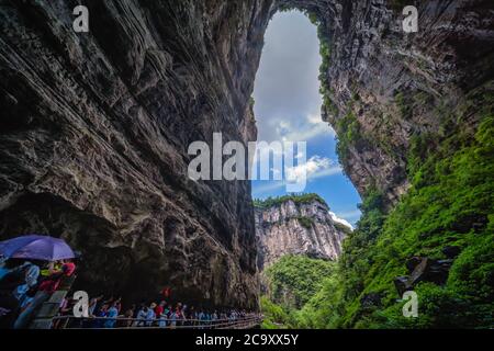 Wulong, Chine - août 2019 : foules de touristes marchant sur un chemin étroit vers la fissure naturelle de l'arche rocheuse dans un canyon parmi le paysage karstique de Banque D'Images