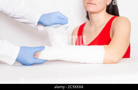 Médecin chirurgien établit un plâtre et un bandage serré sur la main d'une fille avec une fracture offset, le fond Banque D'Images