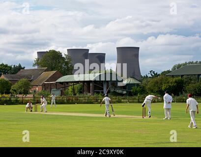 Match de cricket en cours dans le village de Drax, dominé par les tours de refroidissement de Drax Power Station, North Yorkshire, England UK Banque D'Images