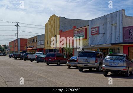 Voitures garées, camions et SUVÕs devant les magasins, peintes dans diverses couleurs sur une rue de Rosenberg au Texas. Banque D'Images