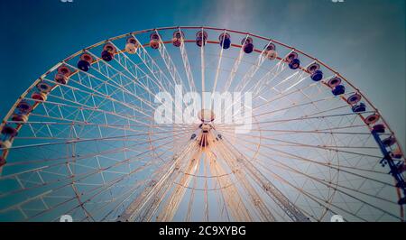 Grande roue colorée contre un ciel bleu clair dans un parc d'attractions pendant l'après-midi Banque D'Images