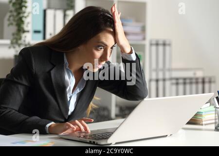 Surprise femme de direction découvrant une erreur sur un ordinateur portable assis sur un bureau Banque D'Images