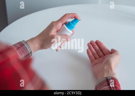 Femme pulvérisant un antiseptique sur les mains - gros plan, foyer sélectif, vue sur l'épaule. Désinfection par pulvérisation, protection, prévention, COVID-19, coronavirus Banque D'Images
