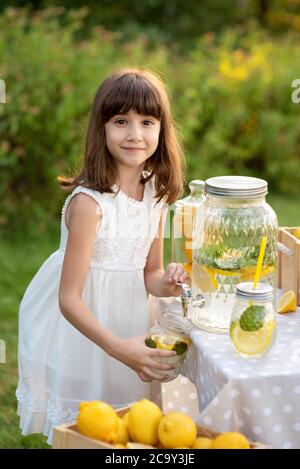 La petite fille vend de la limonade naturelle au stand dans le parc. Banque D'Images