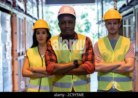 Portrait african Black Warehouse Supervisor stand et a traversé ses bras avec son équipe interraciale dans le grand centre de distribution d'entrepôt. Logiciels professionnels Banque D'Images