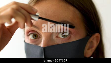 Femme dans le masque de protection applique mascara Banque D'Images